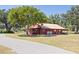 Charming red barn with a metal roof, surrounded by mature trees and a well-maintained landscape at 602 Cr 489, Lake Panasoffkee, FL 33538