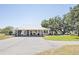 Wide shot of the property showcasing a metal roof, car port, long driveway, and mature landscaping at 602 Cr 489, Lake Panasoffkee, FL 33538