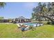 A stunning pool area with lounge seating complements a charming home surrounded by sprawling green lawns at 602 Cr 489, Lake Panasoffkee, FL 33538