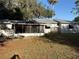 Rear view of the house shows the screened in porch and windows plus a metal roof in a grassy back yard at 608 Gray Ave, Wildwood, FL 34785