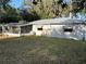 A rear view of a single-story home featuring a screened porch, windows, metal roof, and grassy backyard at 608 Gray Ave, Wildwood, FL 34785