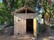 Close-up of an outdoor wooden shed with a partially open door and trees in the background at 608 Gray Ave, Wildwood, FL 34785