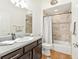 Clean bathroom features brown wood vanity, granite counters and a tiled shower and tub at 857 Enisgrove Way, The Villages, FL 32163