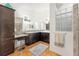 Bathroom featuring double sinks, dark wood cabinets, a vanity, and glass block at 857 Enisgrove Way, The Villages, FL 32163