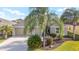 Front of home with a 3-car garage, lovely landscaping, and mature trees at 857 Enisgrove Way, The Villages, FL 32163