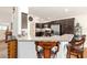 Open kitchen bar area leading into a modern kitchen with stainless appliances and dark cabinetry at 857 Enisgrove Way, The Villages, FL 32163
