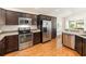 Modern kitchen featuring stainless steel appliances, dark cabinetry, and laminate wood flooring at 857 Enisgrove Way, The Villages, FL 32163