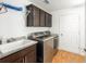 Well-lit laundry room features stainless steel washer and dryer with dark wood cabinets and a utility sink at 857 Enisgrove Way, The Villages, FL 32163