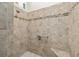 Walk-in shower featuring neutral tile, a hand rail, and a built-in bench at 857 Enisgrove Way, The Villages, FL 32163