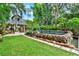 Backyard featuring lush greenery, large stone waterfall, and outdoor dining area at 9642 Bear Lake Rd, Apopka, FL 32703