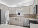 Modern kitchen featuring stainless steel appliances, white cabinets, and a stylish backsplash with an open window to the outside at 9757 Se 175Th Pl, Summerfield, FL 34491