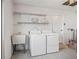 Functional laundry area features white washer/dryer, utility sink, and shelving for storage solutions at 9757 Se 175Th Pl, Summerfield, FL 34491
