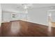 Open-concept living room features dark hardwood floors, ceiling fan, and plenty of natural light with a door to the kitchen at 9757 Se 175Th Pl, Summerfield, FL 34491