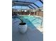 Screened-in pool area with clear blue water, lush landscaping, and shaded seating, perfect for relaxation at 11362 Zimmerman Path, Oxford, FL 34484
