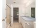 Bright bathroom featuring a walk-in shower with grab bar, single sink vanity with blue countertop, and neutral tiled floor at 1212 Chaparral Dr, Lady Lake, FL 32159