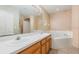 Clean bathroom with double vanity, large mirror, a soaking tub perfect for relaxation, and tile flooring at 1307 Rain Forest Ln, Minneola, FL 34715