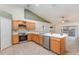 Open kitchen layout with wood cabinets, stainless steel appliances, and breakfast bar at 1307 Rain Forest Ln, Minneola, FL 34715