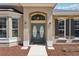 Detailed view of the arched entryway with elegant double doors and a landscaped yard at 13301 Biscayne Dr, Grand Island, FL 32735