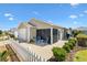 Charming backyard with white picket fence, screened lanai, landscaped yard, and patio with outdoor seating at 1486 Olympia St, The Villages, FL 32163
