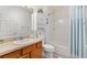 Bright bathroom featuring a vanity with a sink, white toilet, and a shower with blue curtains at 1486 Olympia St, The Villages, FL 32163
