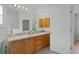 Bathroom with dual vanities, wood cabinets and a large mirror lit by sconces above at 17036 Se 79Th Clearview Ave, The Villages, FL 32162