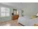 Bedroom with neutral walls, hardwood floors, wooden dresser and ample light from the large window at 17036 Se 79Th Clearview Ave, The Villages, FL 32162