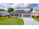 Attractive single-story home featuring a well-kept lawn, mature trees, and a two-car garage at 17036 Se 79Th Clearview Ave, The Villages, FL 32162