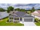 Well-maintained single-story home with a manicured lawn, mature trees, and a two-car garage at 17036 Se 79Th Clearview Ave, The Villages, FL 32162