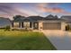 Beautiful single-story home with a well-kept lawn, screened garage, and inviting entrance at sunset at 17036 Se 79Th Clearview Ave, The Villages, FL 32162