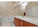 Cozy bathroom with floral wallpaper, single sink vanity, and neutral colored walls at 1721 Sunset Ridge Dr, The Villages, FL 32162