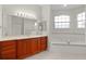 This bathroom features a large vanity, soaking tub, and large bright mirror at 1721 Sunset Ridge Dr, The Villages, FL 32162