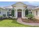 Charming home entrance features a brick path, manicured bushes, and decorative columns at 1721 Sunset Ridge Dr, The Villages, FL 32162