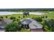 Beautiful home with a well-manicured lawn, mature trees, and brick paved driveway overlooking a golf course and a lake at 1721 Sunset Ridge Dr, The Villages, FL 32162