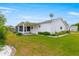 Spacious backyard with green grass, mature landscaping, and a covered patio area at 17587 Se 95Th Cir, Summerfield, FL 34491