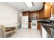 Kitchen featuring wood cabinets, granite countertops, white appliances, and a breakfast table at 17587 Se 95Th Cir, Summerfield, FL 34491