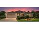 Inviting single-story home with a two-car garage, lush landscaping, and warm exterior lighting at dusk at 1875 Saybrook Way, The Villages, FL 32162