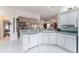 Bright kitchen features white cabinets, a sink, a dishwasher and an open view to the dining and living areas at 1875 Saybrook Way, The Villages, FL 32162