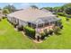 The back of the home with a screen enclosed lanai and lush landscaping at 1875 Saybrook Way, The Villages, FL 32162
