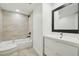 Bright bathroom featuring a bathtub with shower, modern vanity, and a black framed mirror at 1909 S Atlantic Ave # 311312, Daytona Beach, FL 32118