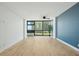 Bright living room featuring wood floors, ceiling fan, large windows with views, and blue accent wall at 1909 S Atlantic Ave # 311312, Daytona Beach, FL 32118