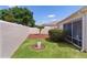 A private backyard featuring a green lawn, a decorative tree, and a privacy wall with access to a screened in lanai at 2128 Alfredo Ave, Lady Lake, FL 32159