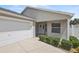 Inviting front entrance with a pristine white garage door, covered porch, and neatly trimmed shrubbery at 2293 Wayland St, The Villages, FL 32162