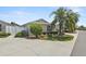 Charming single-story home featuring a well-manicured lawn, lush landscaping, and a mature palm tree at 2293 Wayland St, The Villages, FL 32162