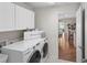 Bright laundry room with white cabinets and modern washer and dryer, adjacent to the main living area at 2293 Wayland St, The Villages, FL 32162
