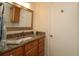 Granite vanity top with wood cabinets, and a framed mirror in bathroom at 2449 Kingstree Pl, The Villages, FL 32162
