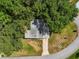 Overhead view of a house nestled among large trees, featuring a paved driveway and manicured lawn at 24802 Pine Hl, Leesburg, FL 34748