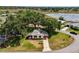 Aerial view of the cozy home featuring a well-manicured lawn, mature trees, and a concrete driveway at 24802 Pine Hl, Leesburg, FL 34748