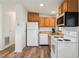 Functional kitchen featuring wooden cabinets, white appliances, and wood-look floors at 24802 Pine Hl, Leesburg, FL 34748