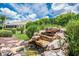 Private back yard includes a rock waterfall feature and beautifully landscaped lawn at 2669 Halsey Ter, The Villages, FL 32162