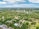 Wide aerial view shows a metal roofed building on a treed lot and other properties surrounding a body of water at 300 Carol Ann Dr, Edgewater, FL 32132